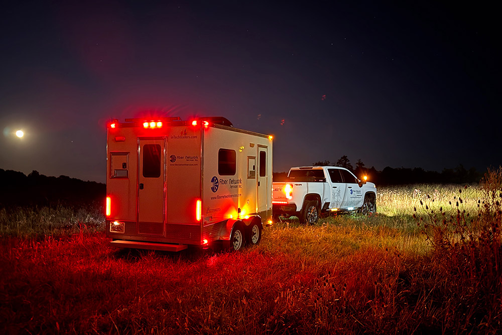 Fiber Network truck and trailer at night headed to an emergency repair